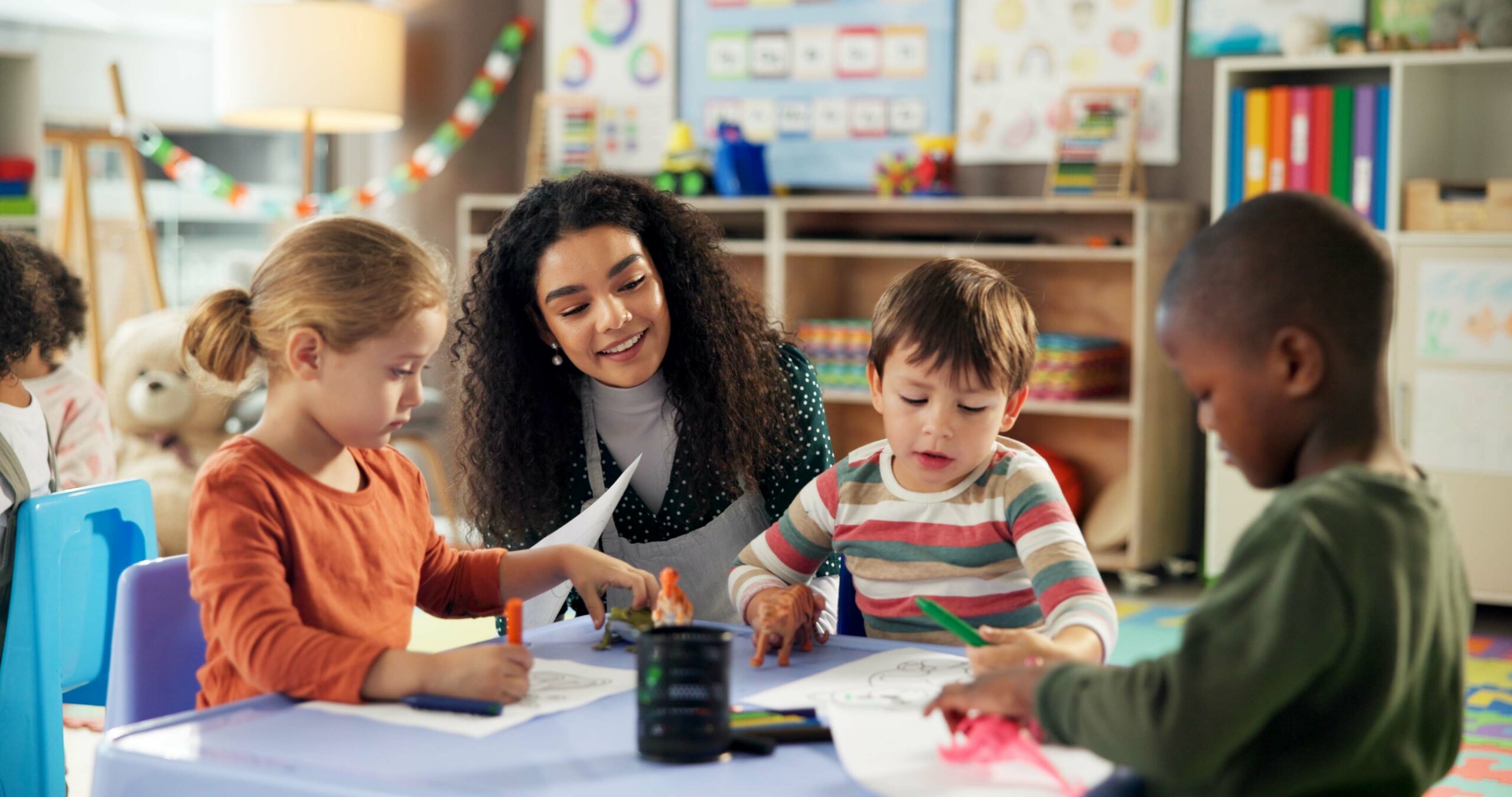Drawing, education and teacher with children in classroom for learning, students and creative art. Growth, kindergarten and academy with woman and kids at school for helping and child development.